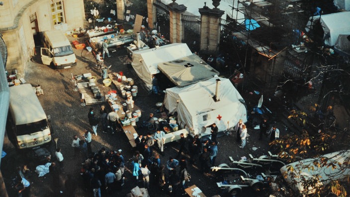 DDR-Flüchtlinge stehen vor Versorgungs-Zelten des DRK im Innenhof der deutschen Botschaft in Prag