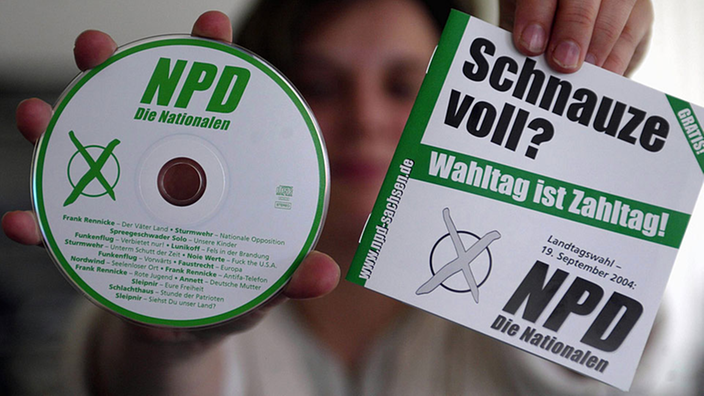 Eine Frau hält in ihren Händen eine CD der NPD und ein Begleitheft.