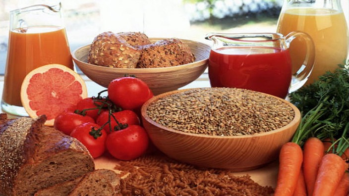 Verschiedene Vollkornprodukte: Brot, Brötchen, Nudeln, Körner, Säfte und Gemüse.