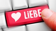 Ein Finger drückt auf eine Computertaste mit der Aufschrift "Liebe"