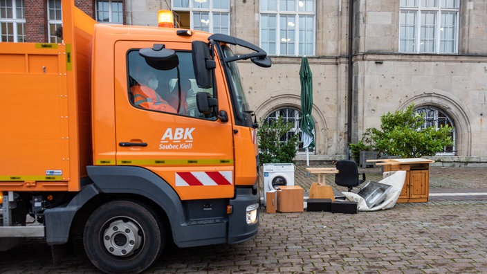 Ein Müllwagen neben einem Haufen Sperrmüll