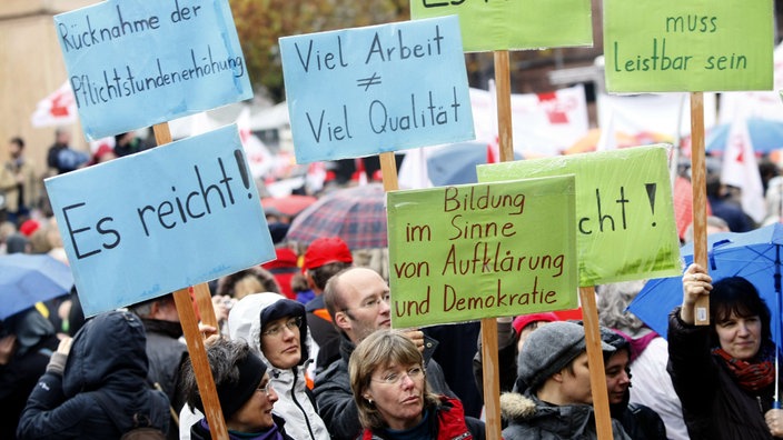 Eine Gruppe von Gewerkschafterinnen und Gewerkschaftern hält Schilder hoch mit Aufschriften wie "Es reicht!" oder "Bildung im Sinne von Aufklärung und Demokratie"