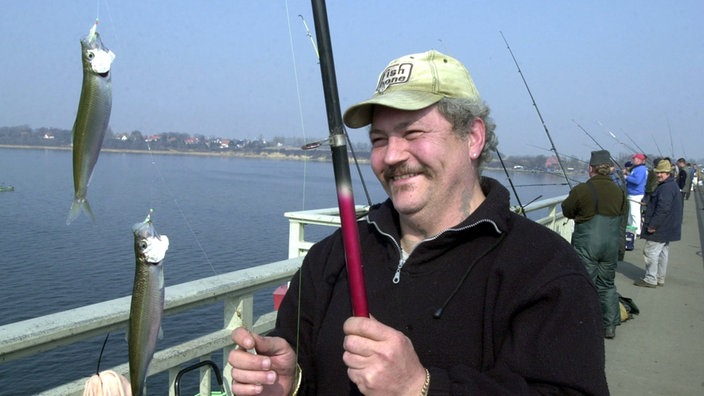 Angler mit Heringen auf Brücke.