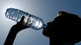 Profil eines Jungen, der aus einer Wasserflasche trinkt.