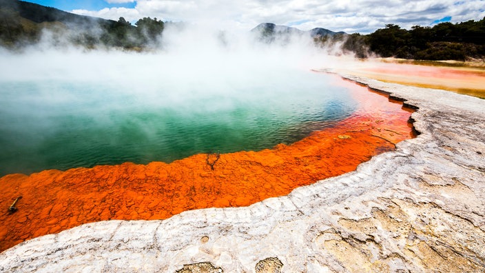 Quelle mit dampfendem Wasser in türkis, grün und orange