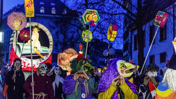 Verkleidete Menschen ziehen trommelnd durch die dunklen Straßen