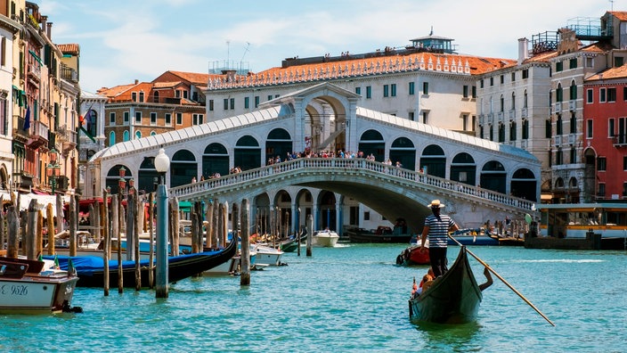 Die Rialtobrücke und der Canal Grande, im Vordergrund ein Gondoliere mit Gondel