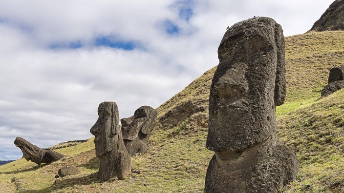 Mehrere große Steinfiguren stehen auf einem Hügel.