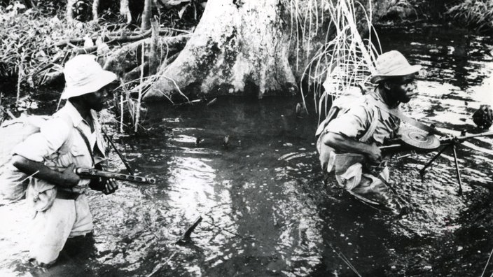 Schwarzweiß-Foto: Zwei Rebellen waten in Angola durch einen Sumpf