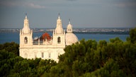 Barockkirche Igreja de Santa Engrácia mit Blick auf die Kuppel und Wasser im Hintergrund.