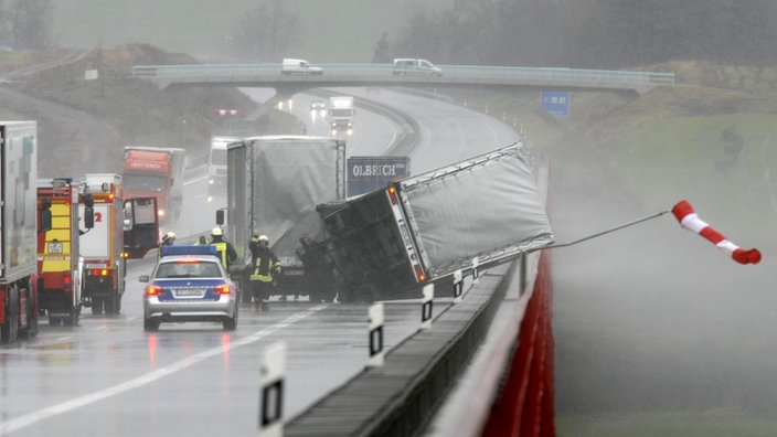 Auf einer Autobahnbrücke hat der starke Wind einen Laster umgeworfen.