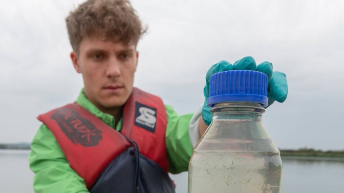 Mann in Boot mit Wasserflasche in der Hand.