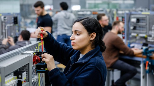 Eine Industrieelektrikerin montiert einen Schaltkreis