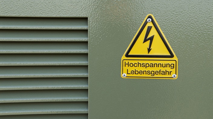 Front einer Trafostation: Graue Blechtür mit gelben Schild 'Hochspannung Lebensgefahr'