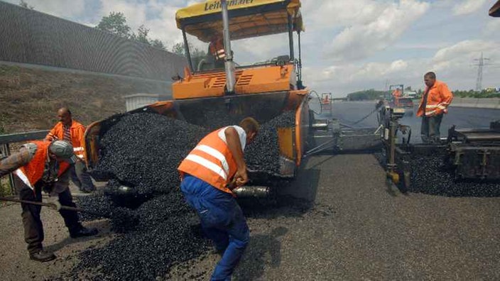 Arbeiter bringen mit modernen Maschinen eine neue Asphaltdecke auf