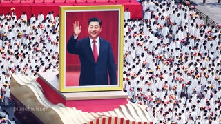 Große Menschenmenge in deren Mitte ein riesiges Porträt des Staats- und Parteichefs Xi Jinping auf einem Podest steht.